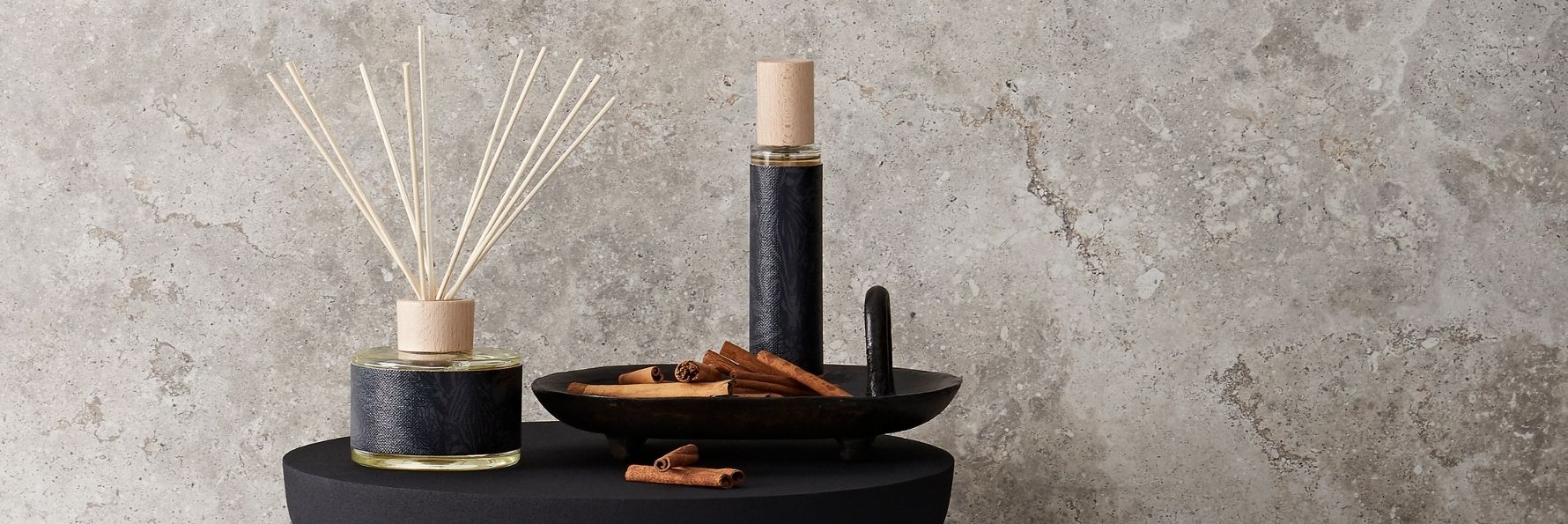 Difusor de varetas e vela aromática da Decoragloba sobre uma parede de pedra